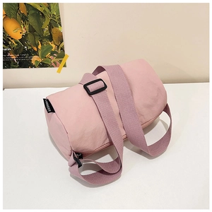 Close-up of pink nylon cylinder crossbody bag featuring adjustable wide fabric strap
