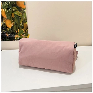 Detail of pink nylon boston bag showing fabric texture and cylinder shape on stand