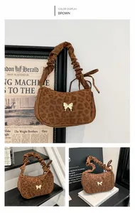 Detail view of leopard print handbag featuring a silver butterfly charm and ruched strap