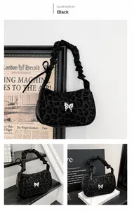 Detail of black leopard print underarm bag with silver butterfly and pleated strap