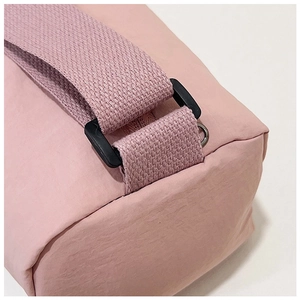 Close-up of pink nylon bag with a wide woven strap and black adjustable plastic buckle
