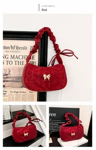 Detail of red suede handbag featuring pleated handle and silver butterfly buckle accent