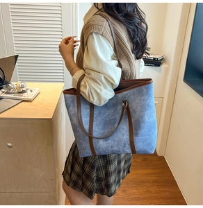 Dettaglio della grande borsa tote in tela blu con manici in pelle marrone in ufficio
