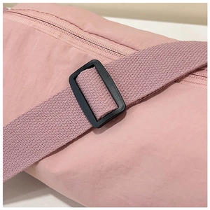 Detail of pink nylon bag showing shoulder strap adjustment buckle and smooth zipper texture