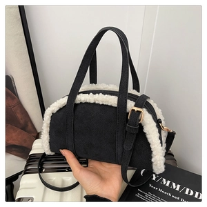 Détail d'un sac polochon en daim noir avec bordure en fourrure blanche et zip doré