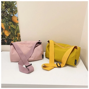 Pink and mustard yellow nylon crossbody bags with adjustable straps in a minimalist setup