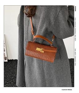 Détail de la texture tressée du sac marron avec fermoir doré et poignée supérieure