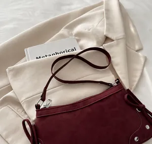 Detail of wine red matte leather shoulder bag with silver zipper and metal rivets decoration