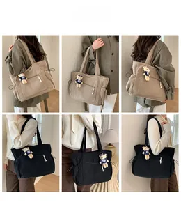 Detail view of large corduroy tote bag showing side drawstring pockets and teddy bear charm