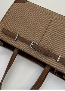 Detail of vintage brown twill tote bag showing leather strap and silver metal buckle