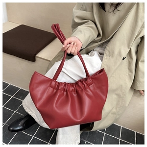 Detailed view of dark red matte leather tote with elegant ruched design and slim handles