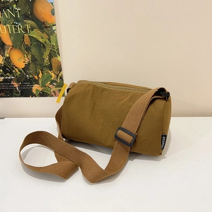 Brown nylon cylinder crossbody bag with adjustable wide strap and minimalist design