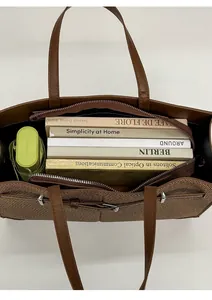 Top view of spacious interior of brown leather tote bag with books and an umbrella