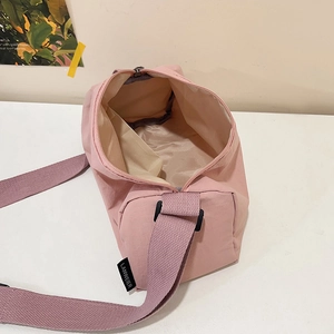 Pink waterproof nylon crossbody bag with wide strap and spacious interior compartment