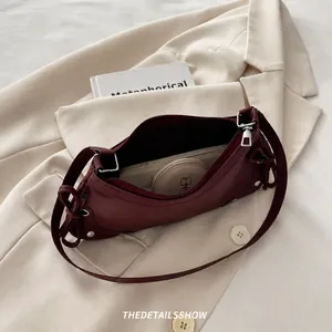 Interior capacity of burgundy crescent bag with studs showing phone and essentials