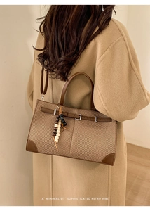 Detail of retro houndstooth tote bag with brown leather trim and beaded tassel accent