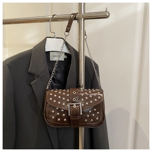 Détail du sac à bandoulière en cuir verni marron foncé avec clous et boucle en métal