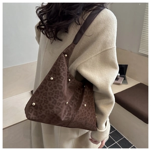Detaillierte Seitenansicht einer Hobo-Tasche mit Leopardenmuster und goldenen Nieten-Details