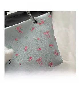 Close-up of seersucker tote bag with pink rose patterns and a plush ball charm