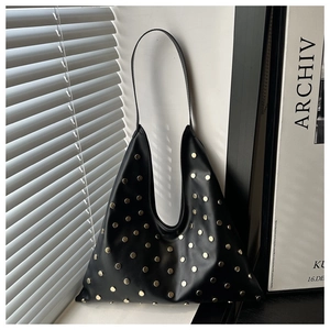 Détail d'un sac porté épaule en cuir noir avec clous dorés et effets d'ombre naturelle