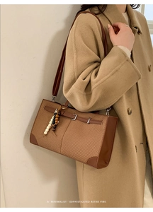 Detail of woven retro tote bag with leather trim and wooden bead charm on wool coat
