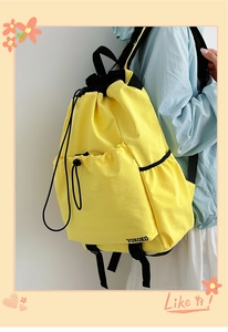 Detail view of yellow drawstring backpack featuring a side mesh pocket and branded logo