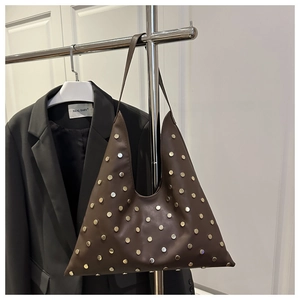 Gros plan du sac cabas en cuir marron avec clous métalliques et structure triangulaire