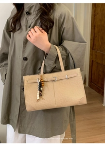 Detail of beige woven tote bag with leather belt buckle and multicolor beaded tassel