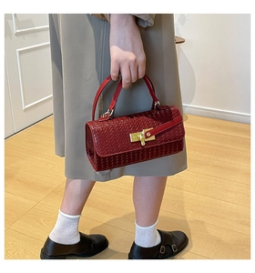 Dettaglio borsa in pelle intrecciata bordeaux con chiusura dorata e tracolla regolabile