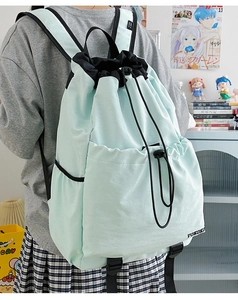 Detail of light blue drawstring backpack showing the spacious front pocket and nylon fabric