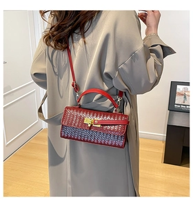 Dettaglio della trama intrecciata e della chiusura dorata sulla borsa bordeaux scuro