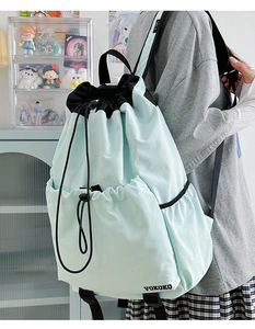 Detail of mint green nylon drawstring backpack featuring black VOKOKO logo and side pocket