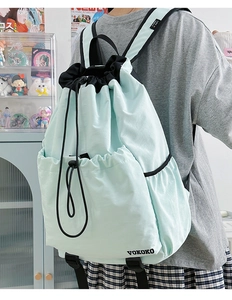 Close-up of mint green drawstring backpack featuring water-resistant nylon and side pocket