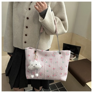 Detail of pink floral tote bag featuring silver chain strap and cute cloud charm pendant