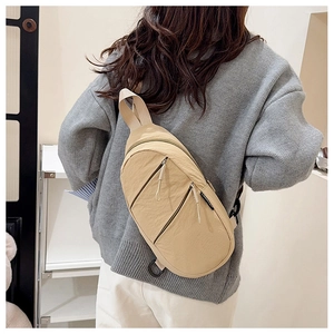 Détail du sac bandoulière beige montrant la texture en nylon et les double zips