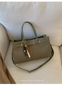 Detail of retro tote bag with olive leather, woven texture and beaded charm