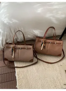 Detail of herringbone fabric tote bag with brown leather trim and wood bead charm