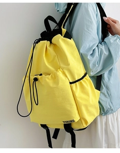 Detail of a bright yellow drawstring backpack featuring a front zipper pocket and VOKOKO logo