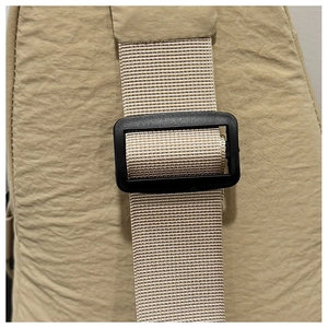Détail macro de la bandoulière réglable en nylon et de la boucle noire sur le sac beige