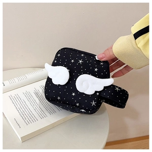 Detail of black canvas mini bag with star print and 3D plush wings on a white table