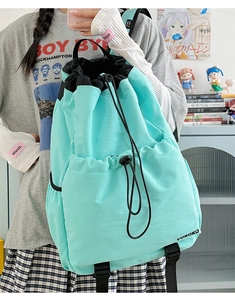 Detail of light blue drawstring backpack with VOKOKO logo and waterproof fabric