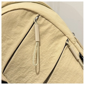 Détails de la fermeture à glissière double avec cordons tressés sur sac à dos beige