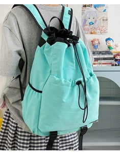 Detail of mint green drawstring backpack showing nylon fabric and side buckle