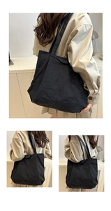 Détail du grand sac cabas noir montrant la texture plissée et l'écusson avec logo FASHION