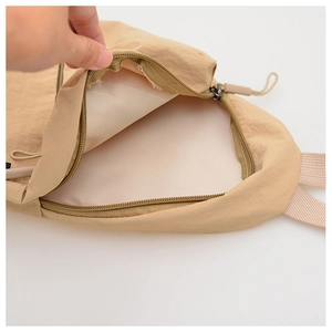Détail d'un sac bandoulière beige montrant la fermeture éclair et la doublure intérieure