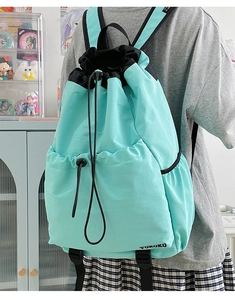 Detail showing mint green and black drawstring backpack worn on shoulders in daily setting