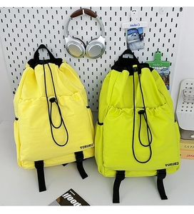 Detail view of yellow and green drawstring backpacks with waterproof nylon texture