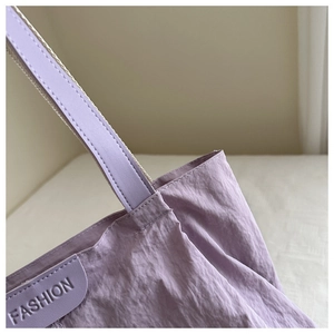 Détail du sac cabas en nylon violet montrant le tissu texturé et le patch embossé