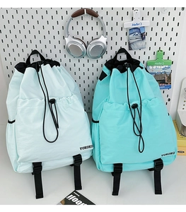 Detail of mint green and blue drawstring backpacks with large front pockets and buckle straps