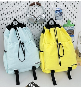 Detail view of light blue and yellow drawstring backpacks with front pockets and buckles